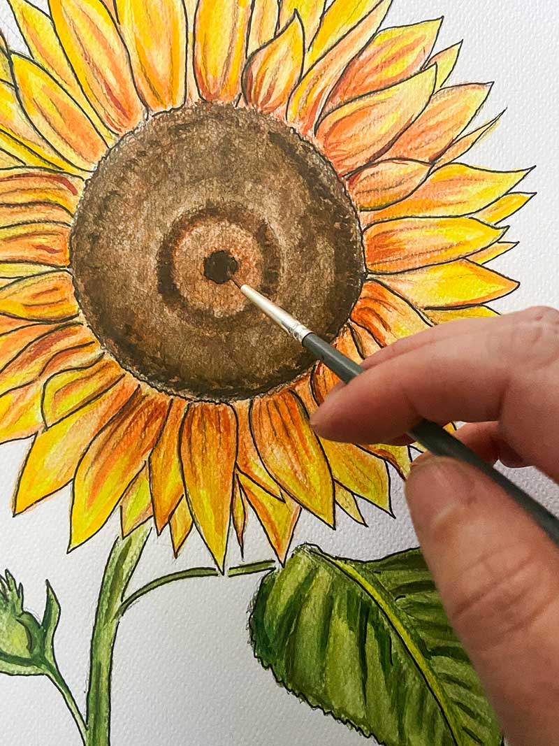 painting center of the sunflower showing hand and brush