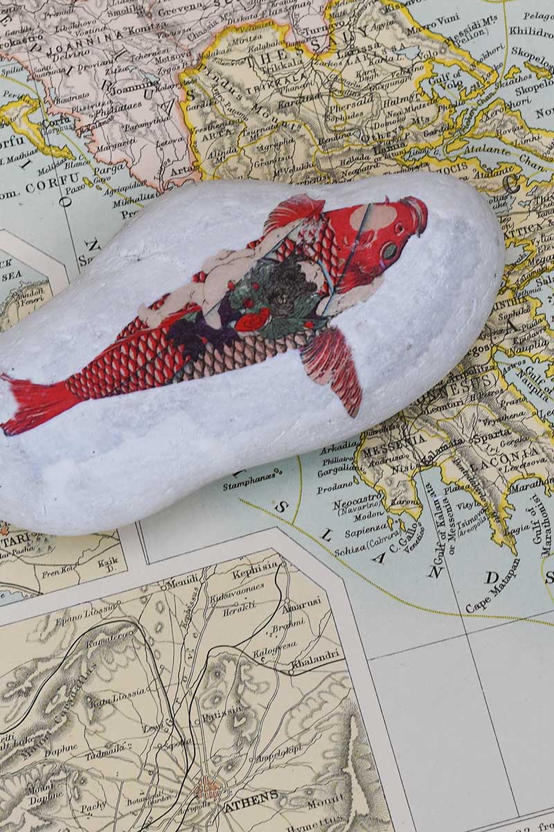 Fish printed rock on pile of maps as a paperweight